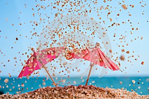 Red umbrellas on a beach with sand grains