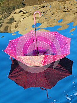 Red upturned umbrella floating on water surface