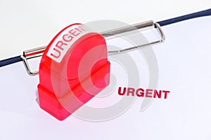 Red urgent stamp on white paper with rubber stamper and clipboard