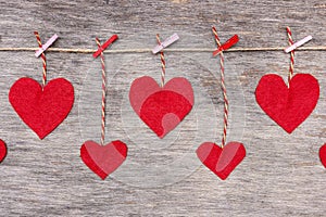 Red Valentine`s love hearts on natural cord and pink pins hanging on rustic driftwood texture background, copy space