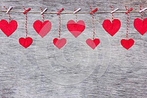 Red Valentine`s love hearts on natural cord and pink pins hanging on rustic driftwood texture background, copy space