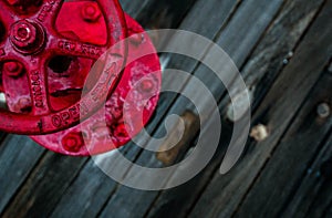 A red valve on the wooden deck of a battleship.