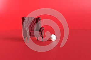 Red velvet armchair of old design on short legs with a soccer ball on black background. 3d rendering