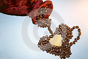 A red velvet bag and coffee beans are laid out in a heart-shaped cup. Roasted coffee beans close up