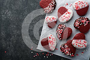 Red velvet or brownie cookies on heart shaped in chocolate icing with red roses on black background. Dessert idea for Valentines