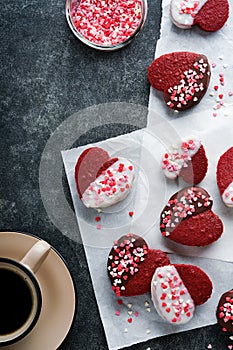 Red velvet or brownie cookies on heart shaped in chocolate icing with red roses on black background. Dessert idea for Valentines