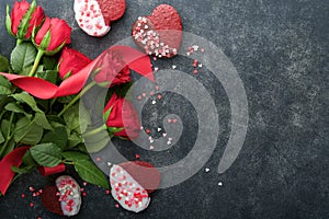 Red velvet or brownie cookies on heart shaped in chocolate icing with red roses on black background. Dessert idea for Valentines