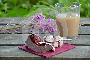 Red velvet cookies next to a cup of coffee. sunny spring or summer morning. pink purple flower
