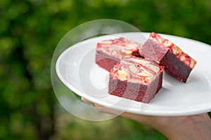 Red velvet cream cheese brownies on white dish