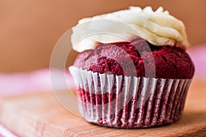 Red Velvet Cupcake with cream on wooden surface.