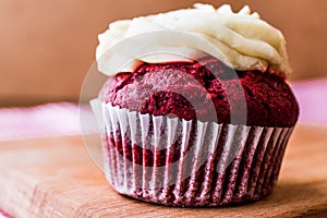 Red Velvet Cupcake with cream on wooden surface.