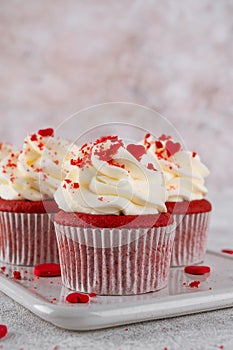 Red velvet cupcakes with cream cheese frosting and red sugar hearts. Delicious dessert for Valentines day. Selective focus