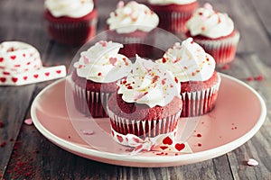 Red velvet cupcakes on a pink dish on a rustic wooden table