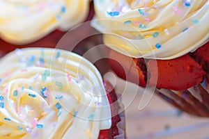 Red velvet cupcakes with white creamy frosting & sprinkles