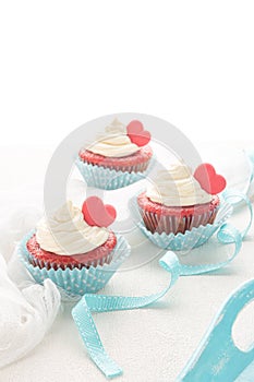 Red velvet heart cupcakes with cream cheese frosting and a red heart for Valentine`s Day. Top view with copy space