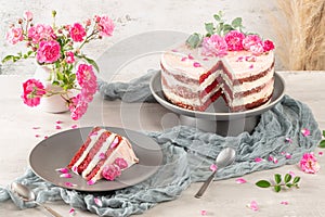 Red velvet naked cake with fresh roses and swiss buttercream on kitchen countertop