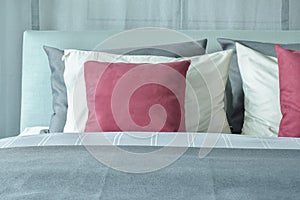 Red velvet pillows with white and gray pillows setting on bed
