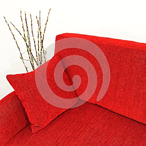 Red velvet sofa and willow branches in a vase