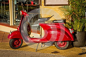 Red Vespa motor scooter on the sidewalk