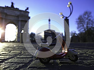 Red vespa parked in front of arco della pace Milan Italy