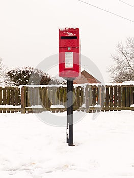 red village post box outside street village with snow winter