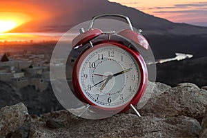 Red vintage alarm clock with beautiful sunrise