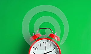 Red vintage alarm clock on green color background