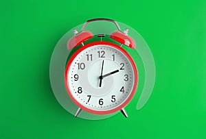 Red vintage alarm clock on light green color background