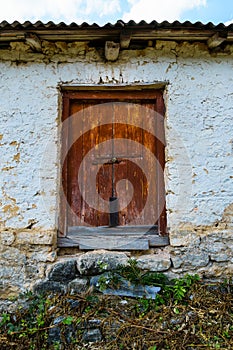 Red vintage door in an old farmhouse or barn, wall painted with white paint