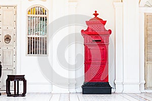 Red and vintage postbox in front of an old building