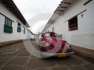 Red vintage retro VW Volkswagen Beetle car vehicle parked in streets road of historic town center Barichara Colombia