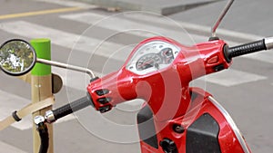 Red vintage scooter standing on city street. Retro scooter parking on citystreet