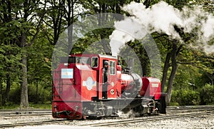 Red vintage steam locomotive moving along railroad tracks