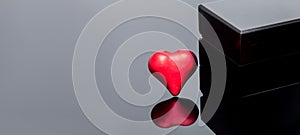 Red volumetric heart near a black gift box.