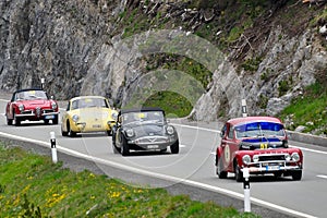 A red Volvo PV544, a dark green Daimler SP250, a yellow Porsche 356 and a red Alfa Romeo Giulia spider