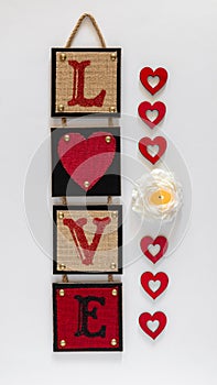 Red wall decor with word love, burning flower candle and hearts. Valentines day and love concept.