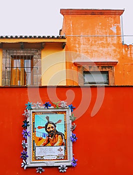 Red wall with religious art in front of historic vintage buildings in san miguel allende Mexico