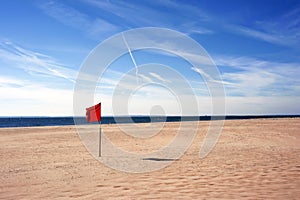 Red warning flag flapping in the wind on beach at sunny day at Coney Island, New York