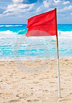 Red warning flag on a stormy beach