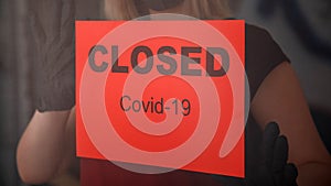 Red warning Sign Closed covid 19 lockdown on front entrance door as new normal shutdown in restaurant. Woman in protective medical