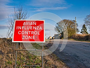 A red warning sign at the side of a road warns that the reader is entering an avian flu control zone.