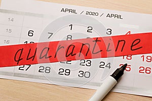 Red warning tape with `quarantine` inscription and black marker on a calendar