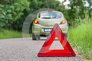 Red warning triangle and broken car on the road