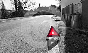 Red warning triangle. Road sign on black and white village background