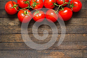 Red washed ripened tomatoes at the top of wooden background