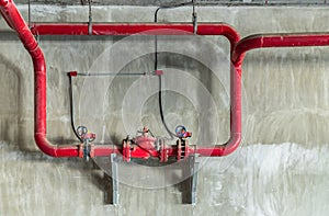 Red water or gas pipeline with gate pressure valve on concrete wall. Industrial tubes and valves, Line pipe industrial and