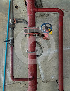 Red water or gas pipeline with gate pressure valve on concrete wall. Industrial tubes and valves, Line pipe industrial and