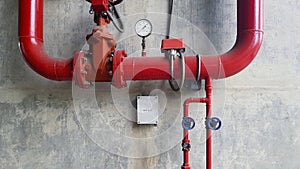 Red water or gas pipeline with gate pressure valve and stainless steel test box installed on concrete wall with copy space.