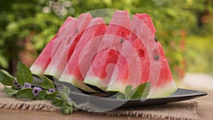 Red watermelon slices on a plate with mint leaves.