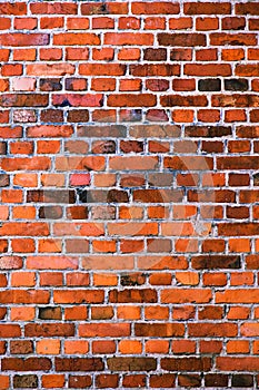 Red weathered old brick wall background, vertical texture. Grunge masonry, exposed vintage building facade.